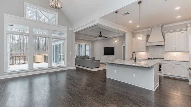Interior real estate photo of an open-concept white kitchen and living room